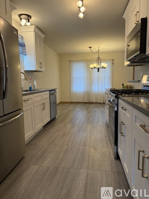 A kitchen with a refrigerator, cabinets, and a stove top oven.