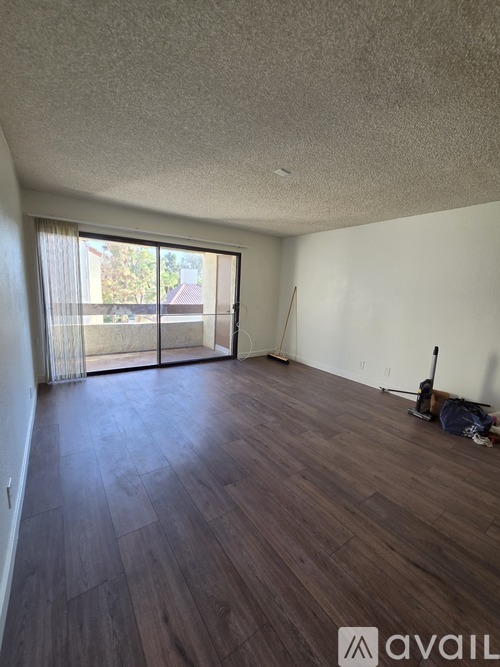 A room with wooden flooring and a sliding glass door leading outside.