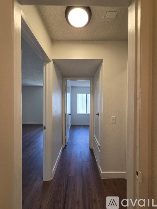 A hallway with wooden floors and white walls.