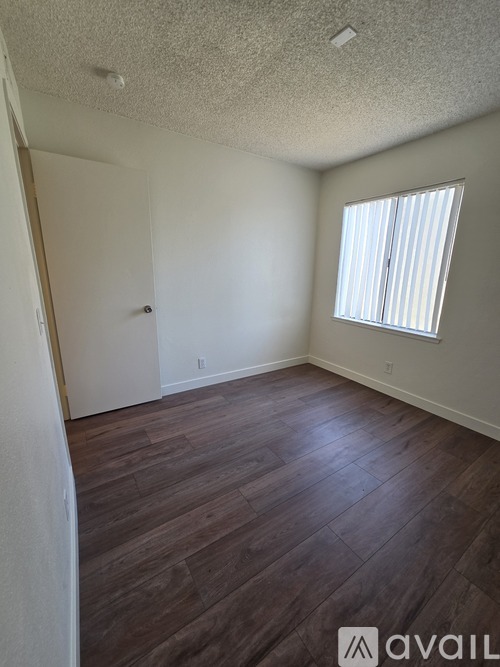 A room with wooden flooring and a window with blinds.
