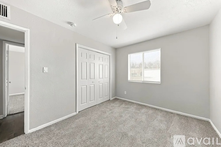 A spacious room with a ceiling fan and two doors.