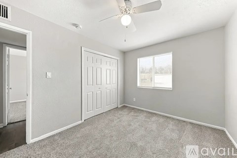 A spacious room with a ceiling fan and two doors.