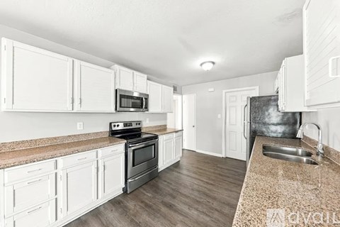 A kitchen with white cabinets and a granite countertop.