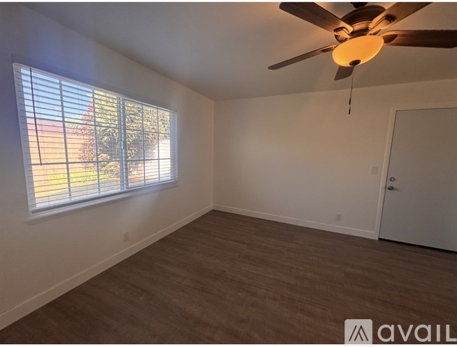 A room with a ceiling fan and a window with blinds.