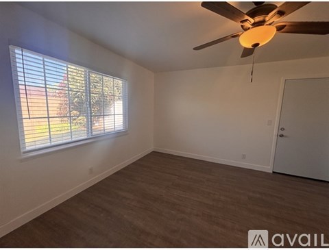 A room with a ceiling fan and a window with blinds.
