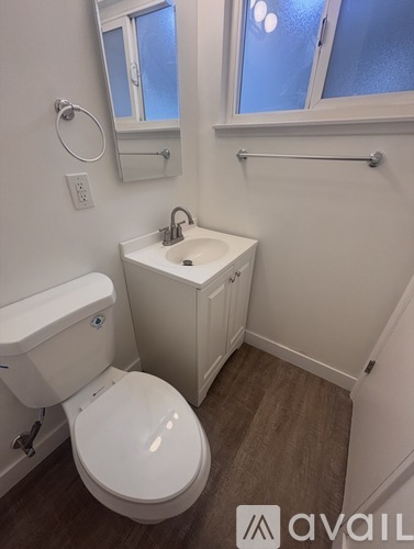 A small bathroom with a toilet, sink, and a window.
