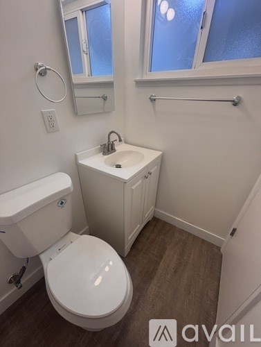 A small bathroom with a toilet, sink, and a window.