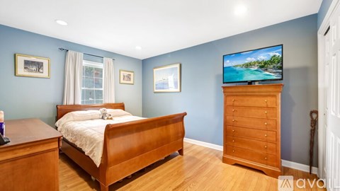 A bedroom with a bed, dresser, and television.