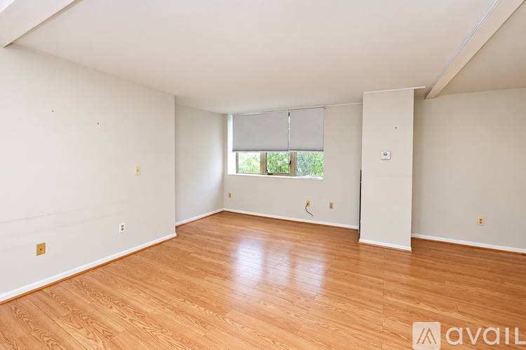 A room with wooden flooring and a window with blinds.