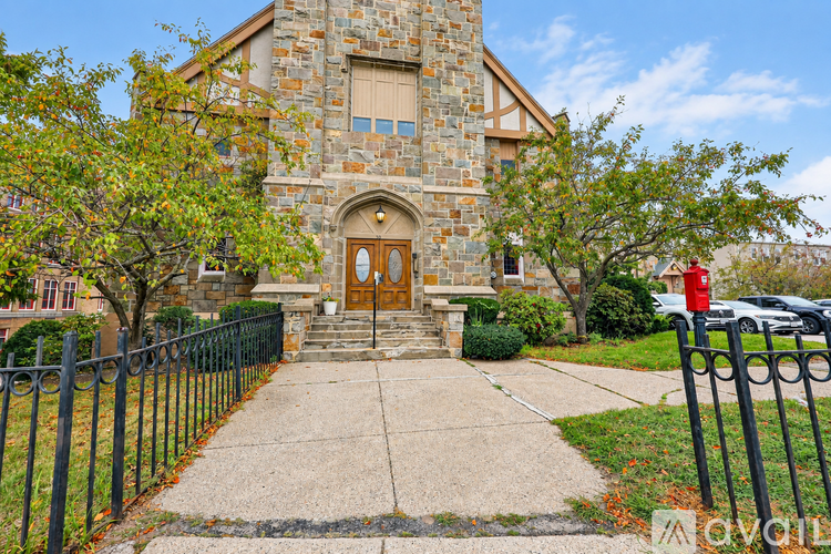 A church with a stone facade and a brown door is surrounded by a black fence.