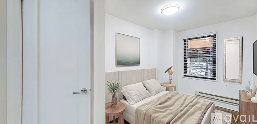 A bedroom with a bed, nightstand, and a window with blinds.