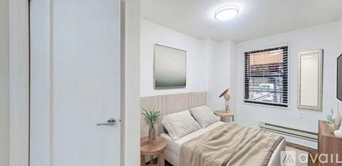 A bedroom with a bed, nightstand, and a window with blinds.