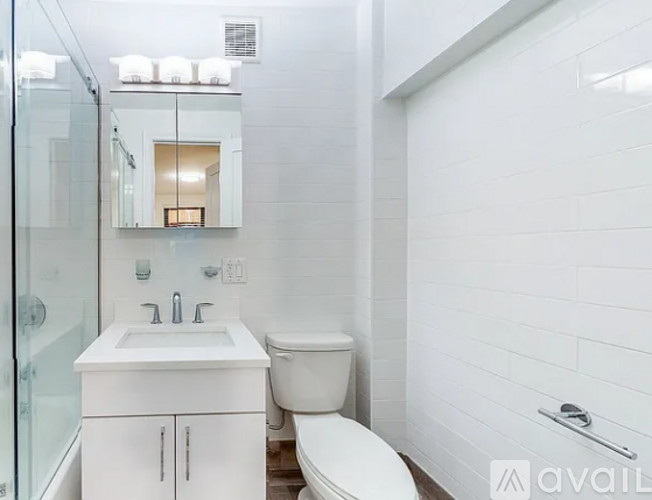 A white bathroom with a toilet, sink, and mirror.