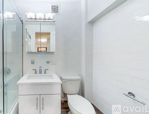 A white bathroom with a toilet, sink, and mirror.