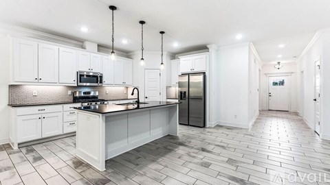 A spacious kitchen with white cabinets and a central island.