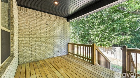 A balcony with wooden flooring and a brick wall.