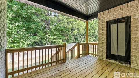 A wooden deck with a glass door leading to a balcony overlooking a forest.