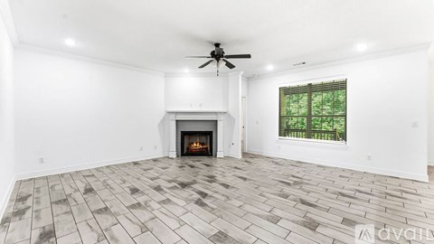 A spacious living room with a fireplace and a ceiling fan.
