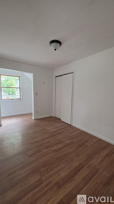 A room with wooden flooring and a window.