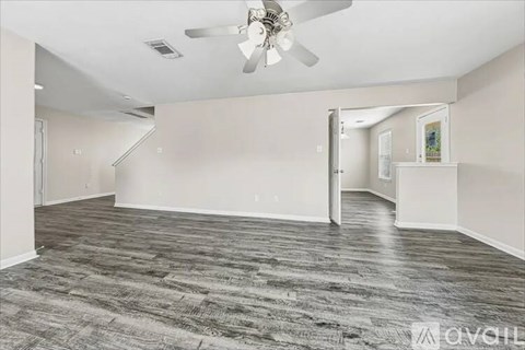 A spacious room with a ceiling fan and carpeted floor.