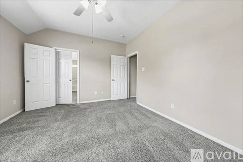 A room with a carpeted floor and a ceiling fan.