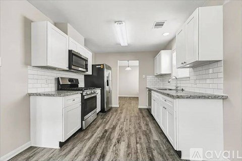 A kitchen with white cabinets and a wooden floor.