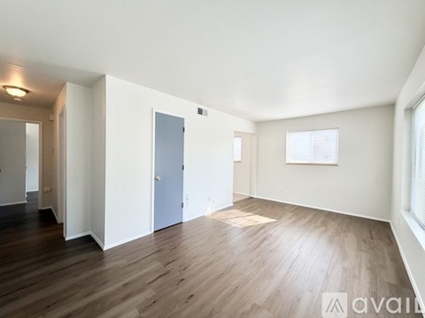A spacious room with wooden flooring and white walls.