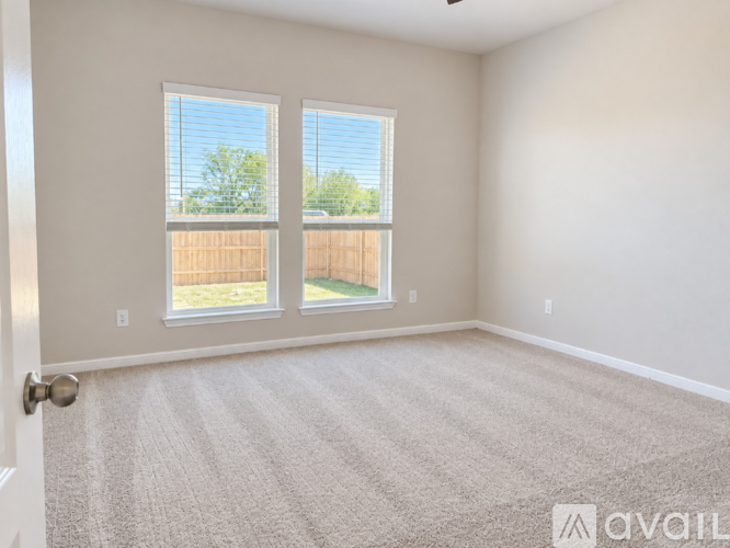 A room with a carpeted floor and two windows.