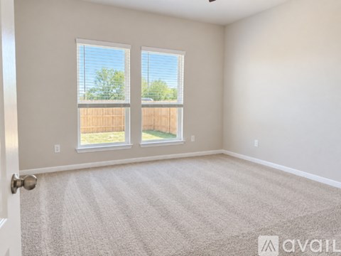 A room with a carpeted floor and two windows.