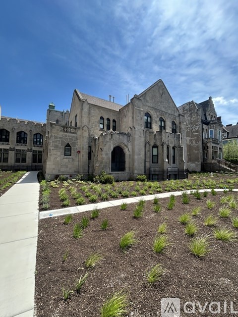 A large, old building with a garden in front.