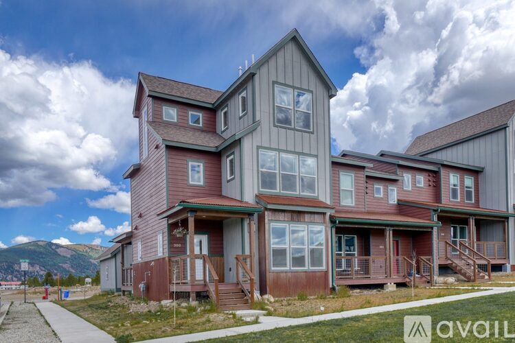 A large multi-story house with a balcony and a mountain in the background.