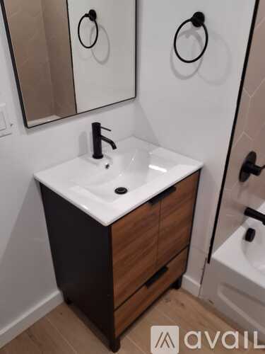 A bathroom sink with a black faucet and a mirror above it.