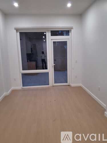 A room with a large window and wooden flooring.