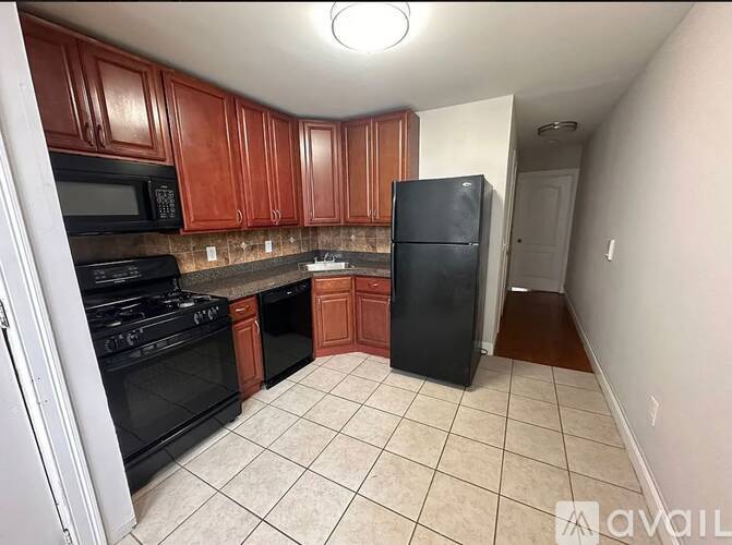 A kitchen with brown cabinets and black appliances.