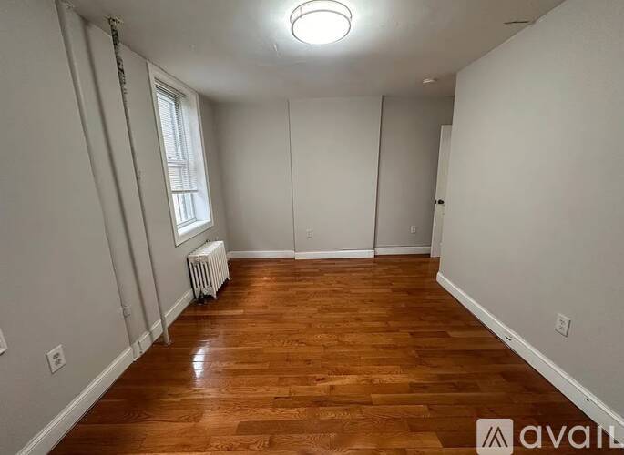 A room with wooden flooring and a window with blinds.