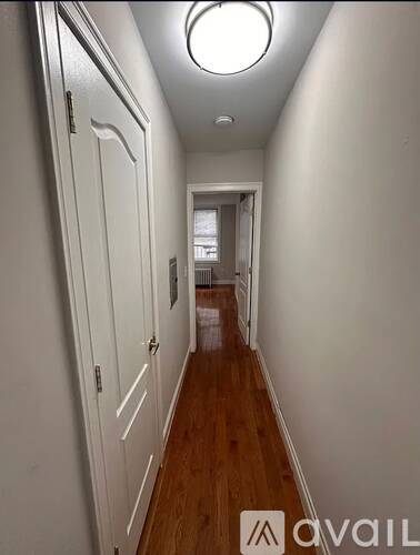 A long hallway with white walls and wood floors.