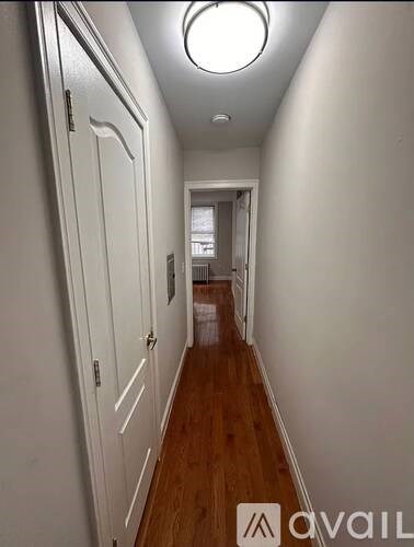 A long hallway with white walls and wood floors.