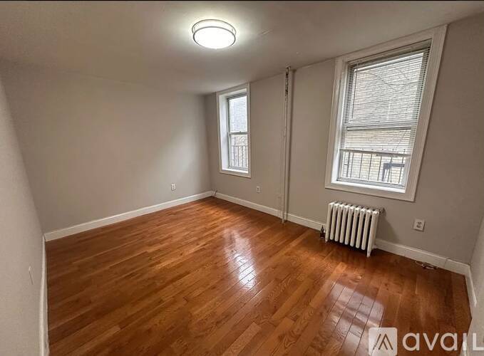 A room with wooden floors and two windows.