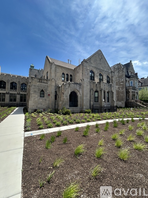 A large, old building with a garden in front.