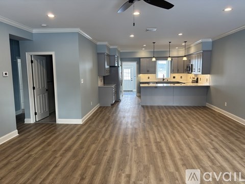 A spacious kitchen and living room with wood flooring and a ceiling fan.