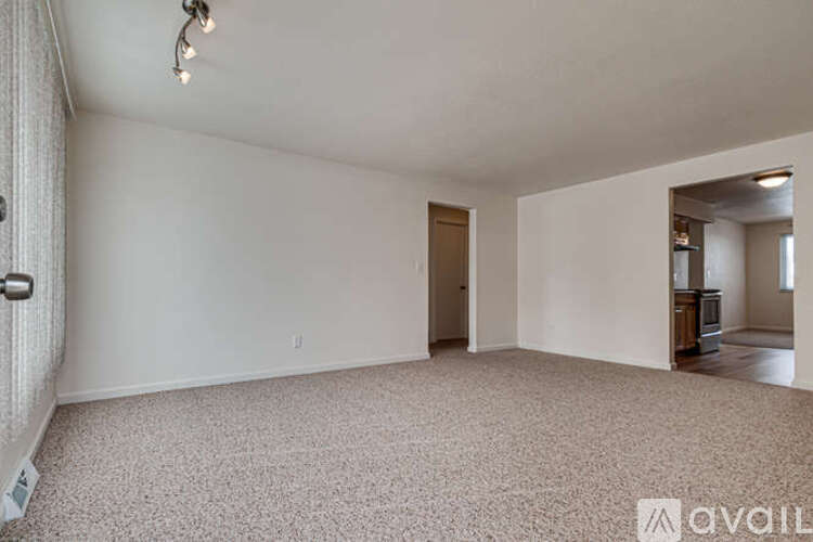 A spacious empty room with a carpeted floor and a door leading to another room.
