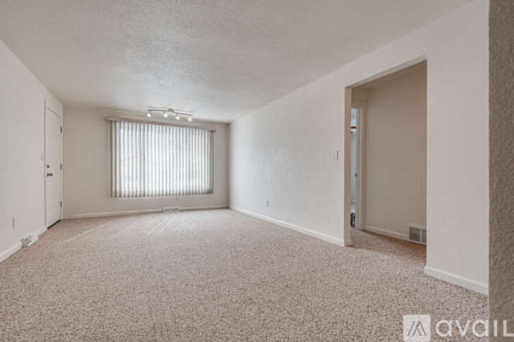 A sparsely furnished room with a window covered by blinds.