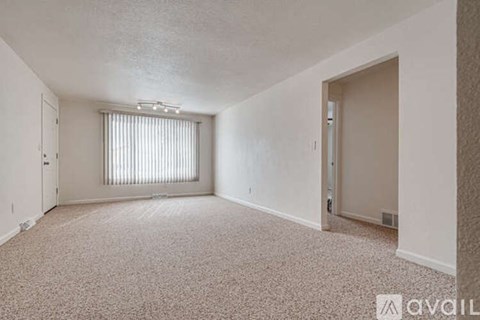 A sparsely furnished room with a window covered by blinds.