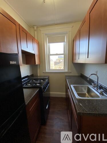 A kitchen with dark wood cabinets and a black fridge.
