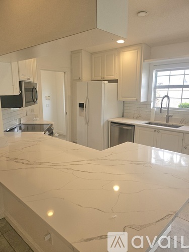 A kitchen with a marble countertop and white cabinets.