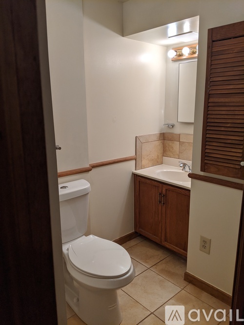 A white toilet in a bathroom with a wooden cabinet.