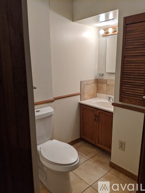 A white toilet in a bathroom with a wooden cabinet.