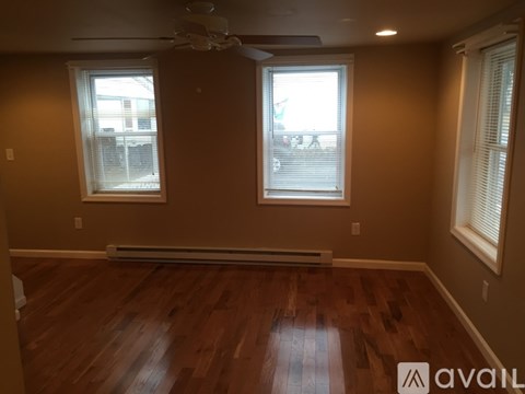 A room with wooden floors and two windows.