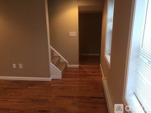A hallway with wooden floors and a staircase.