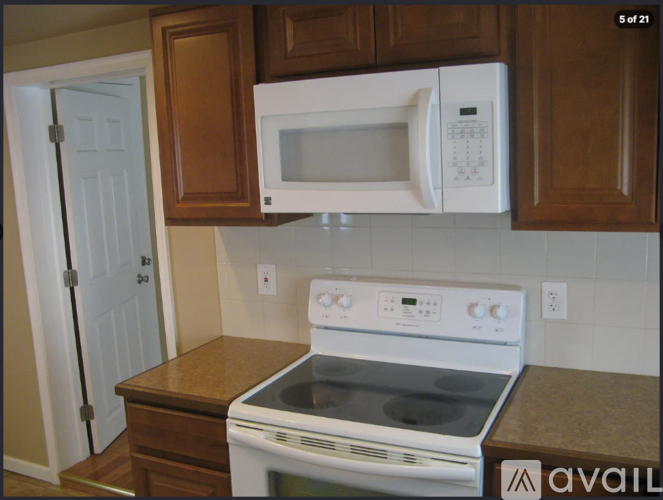 A white microwave oven is mounted above a white stove in a kitchen.